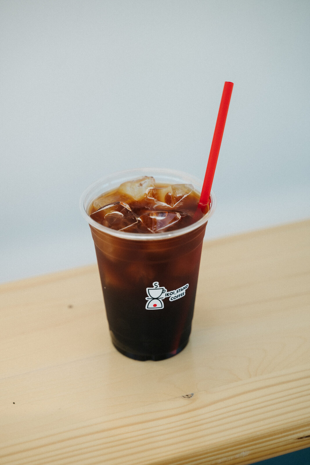 木のカウンターに置かれたいこいスタンドのアイスコーヒー