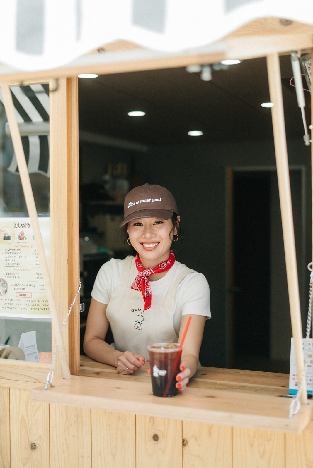 窓口で笑顔で迎えるいこいスタンドの店員さんとアイスコーヒー